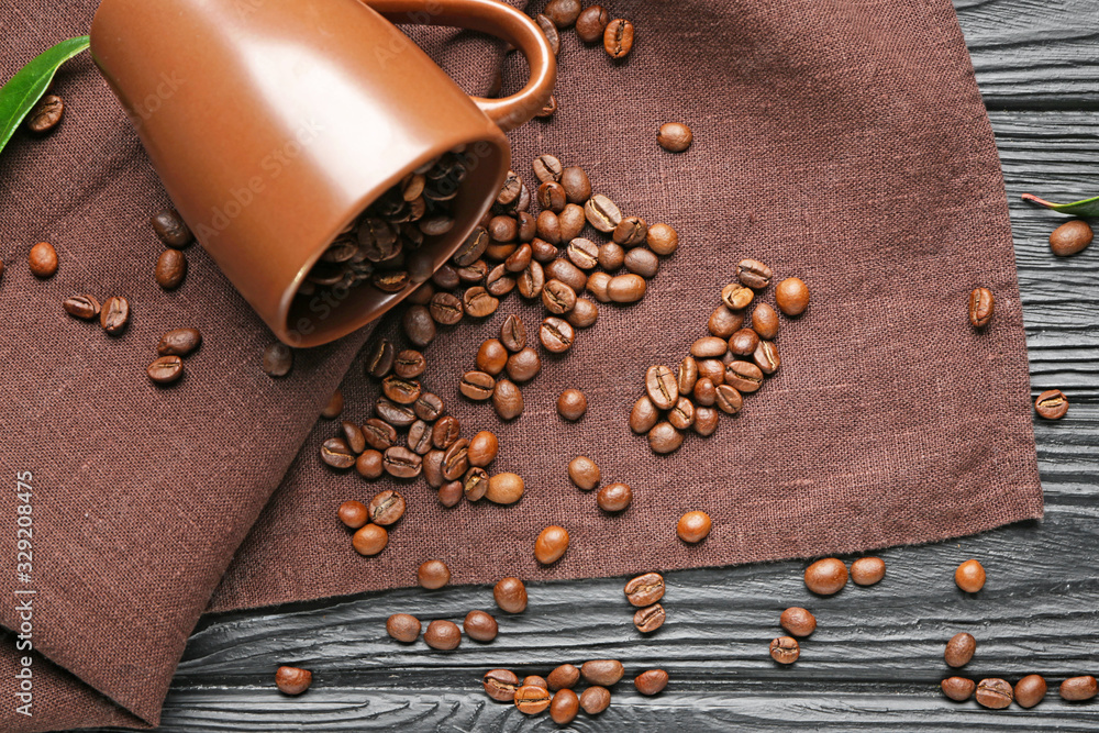 Overturned cup with coffee beans on table