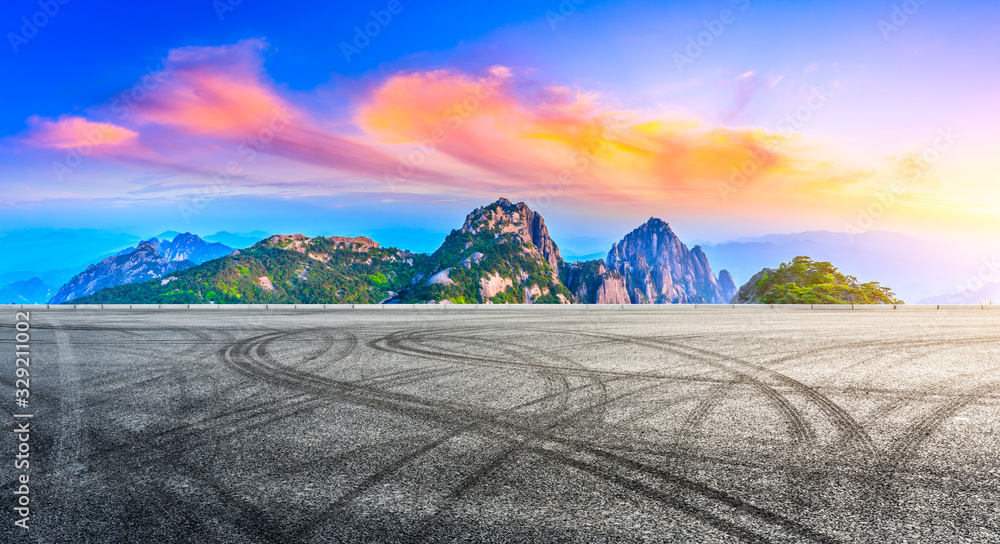 Empty race track road and green mountain with beautiful clouds at sunrise,panoramic view.