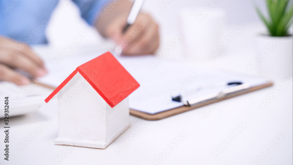 Business concept - Young Asian man in blue shirt calculates, signs agreement contract to buy a house