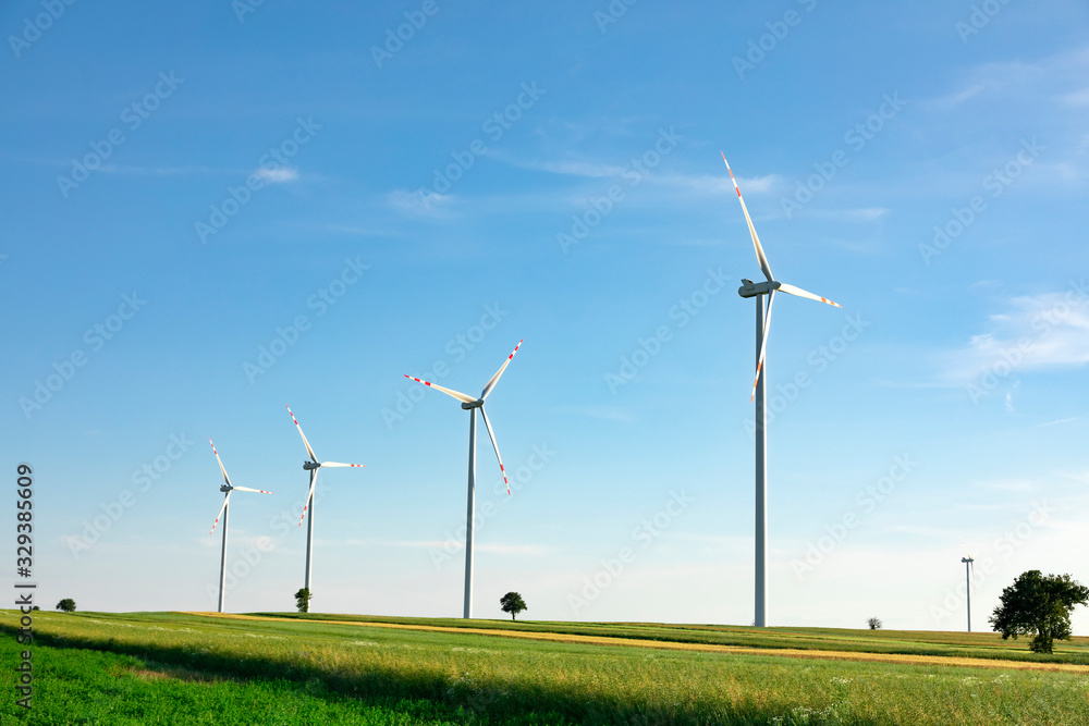 wind turbines in green field, countryside area with blue sky