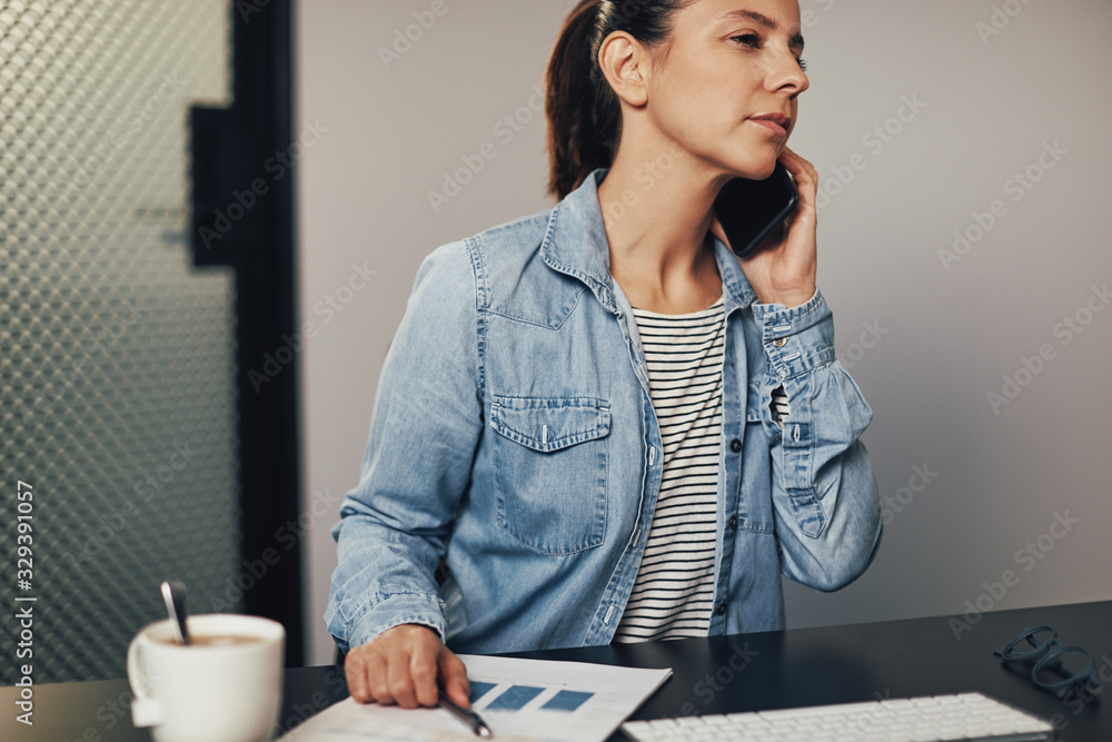 Businesswoman talking on her cellphone while working at her desk