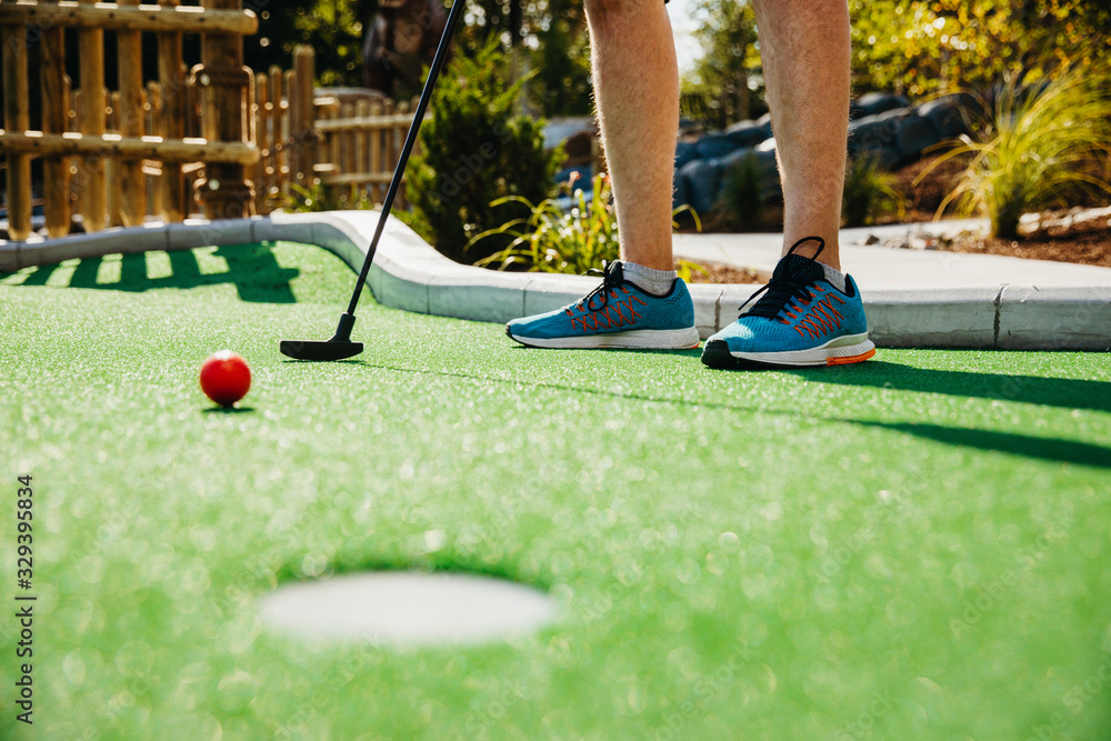 Low section of man taking shot at golf course in Raptor Falls Mini Golf