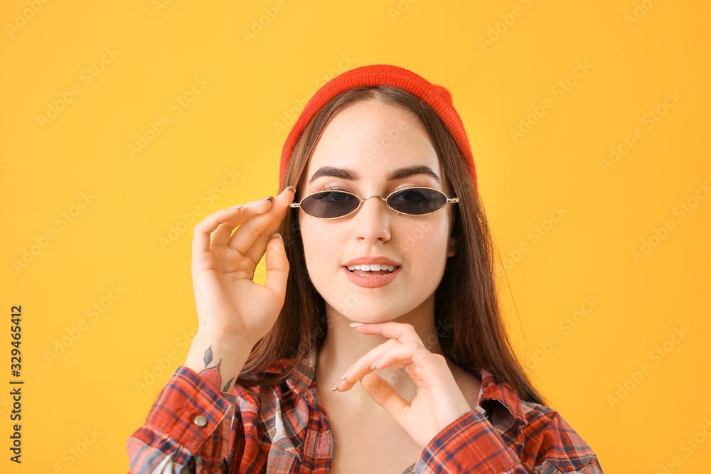 Young woman with stylish sunglasses on color background