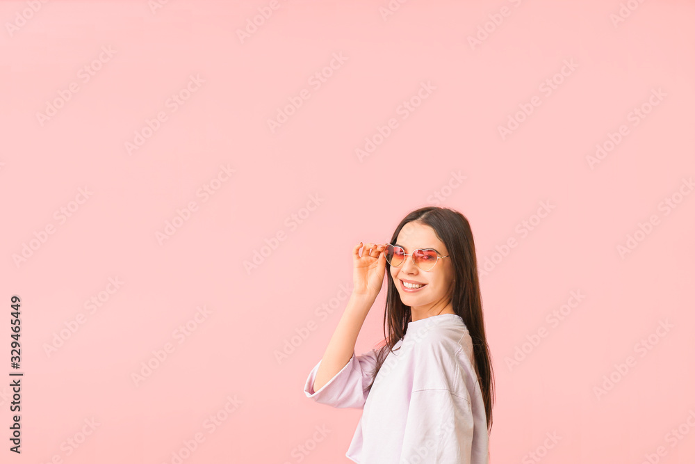 Young woman with stylish sunglasses on color background