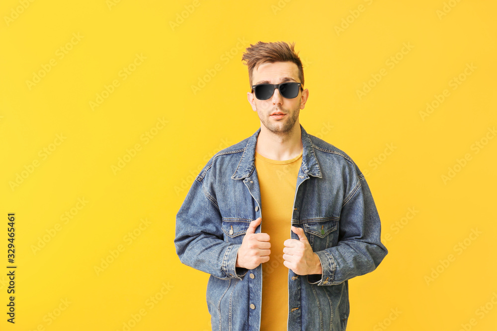 Young man with stylish sunglasses on color background