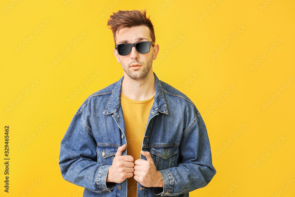 Young man with stylish sunglasses on color background