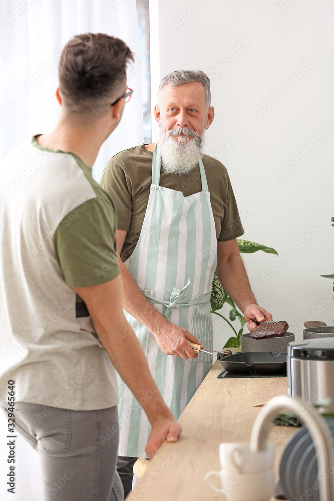 老人和他成年的儿子一起在厨房做饭