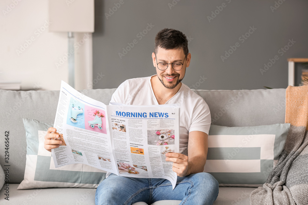 Man wearing glasses while reading newspaper at home