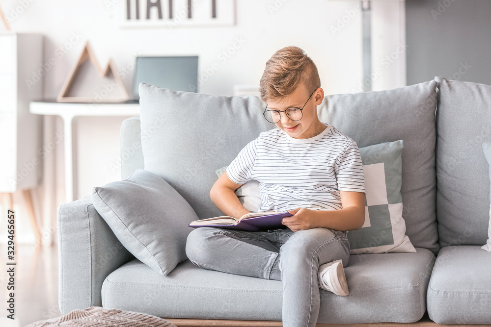 Little boy wearing glasses while reading book at home