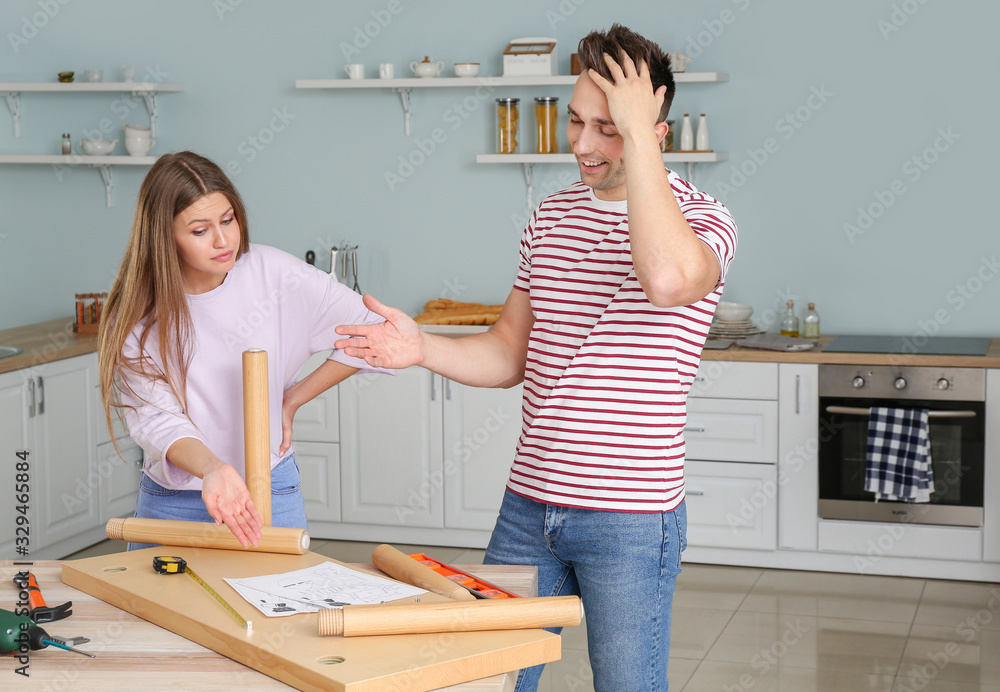 Emotional couple assembling furniture at home