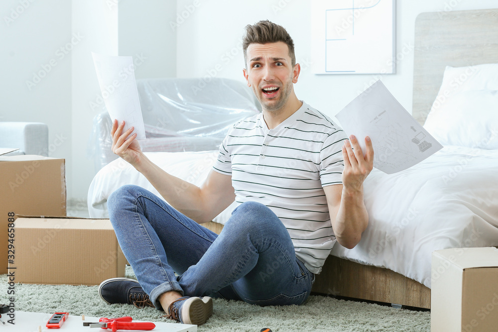 Stressed man assembling furniture at home