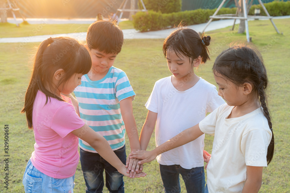 Group of happy young Asian children pile or stack hands togerther outside in city park playground in