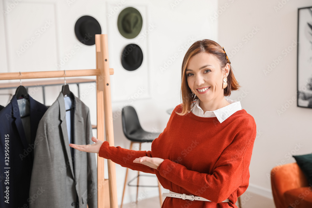 Female stylist near rack with male clothes in her studio