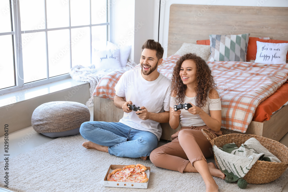 Happy young couple playing video games in bedroom