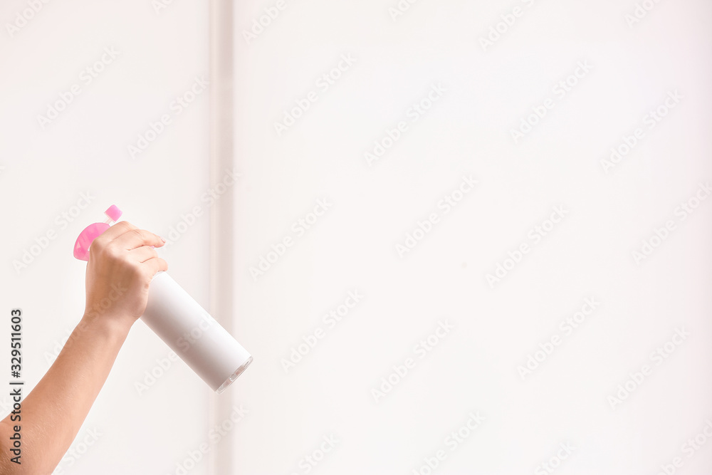 Woman spraying air freshener at home