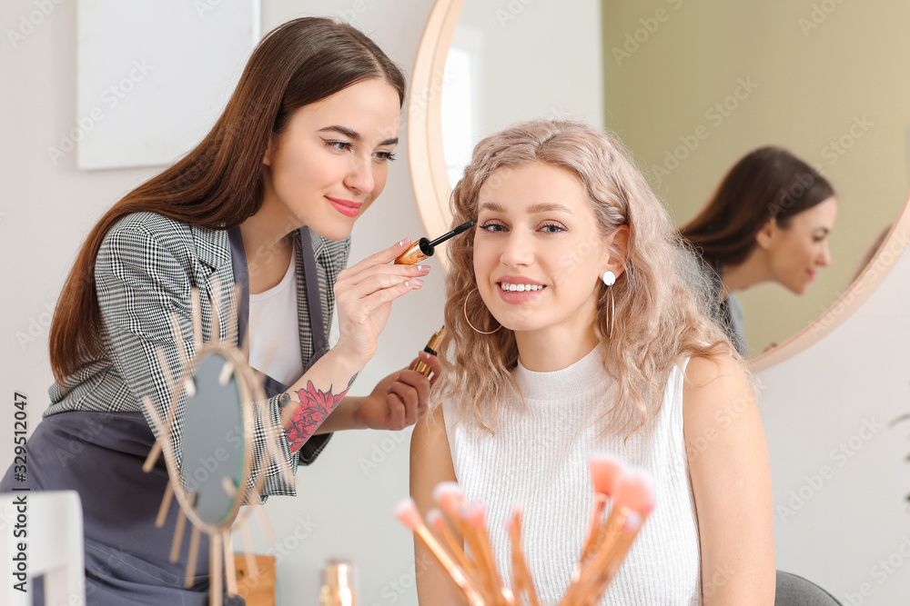 Professional makeup artist working with young woman in salon