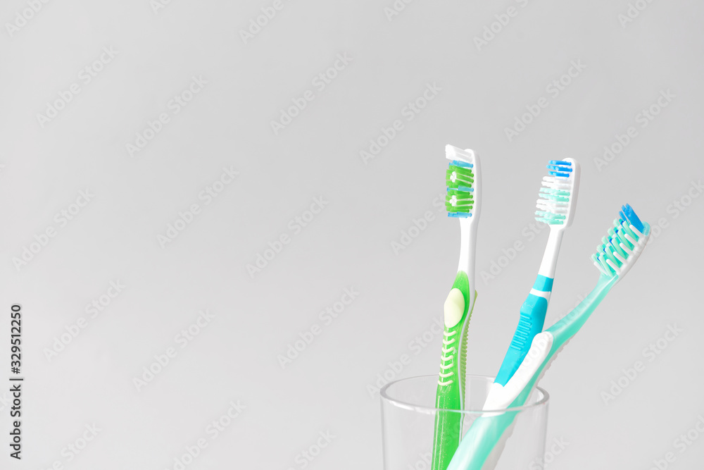 Tooth brushes in glass on light background