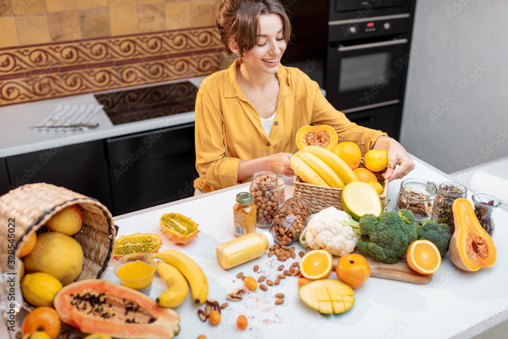 Young and cheerful woman cooking with a variety of fresh vegetables and fruitson the kitchen at home