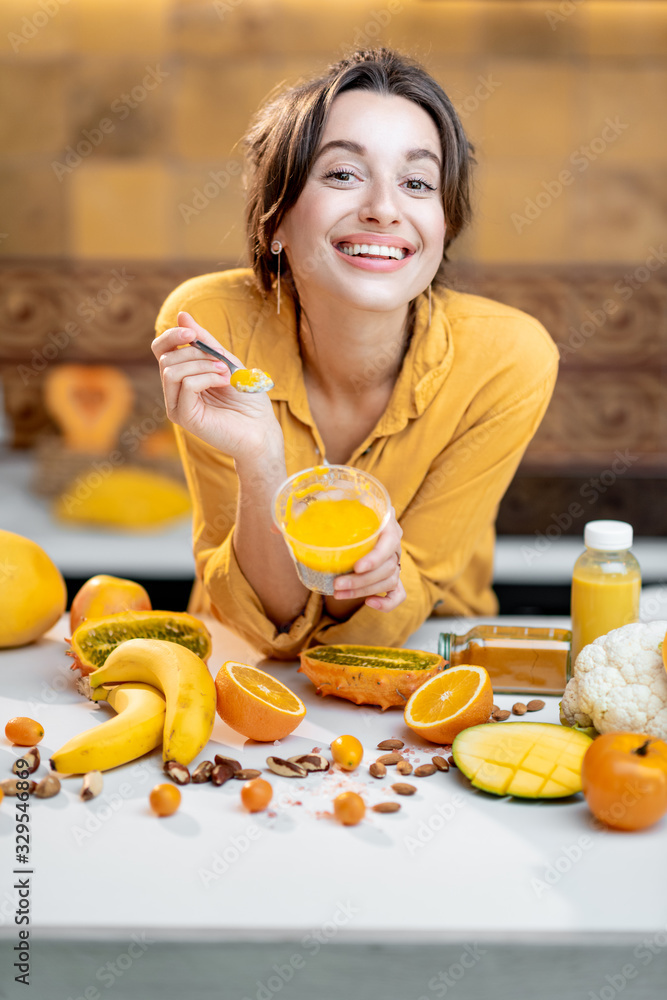 Portrait of a young and cheerful woman eating chia pudding, having a snack or breakfast in the kitch