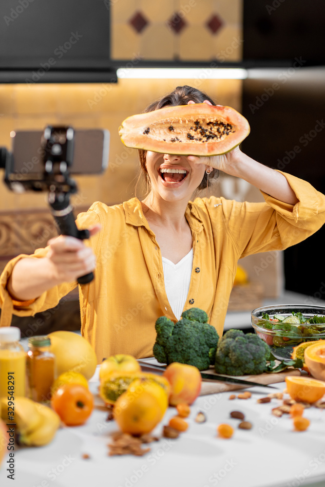 Young and cheerful woman vlogging on mobile phone about healthy food and cooking. Concept of healthy