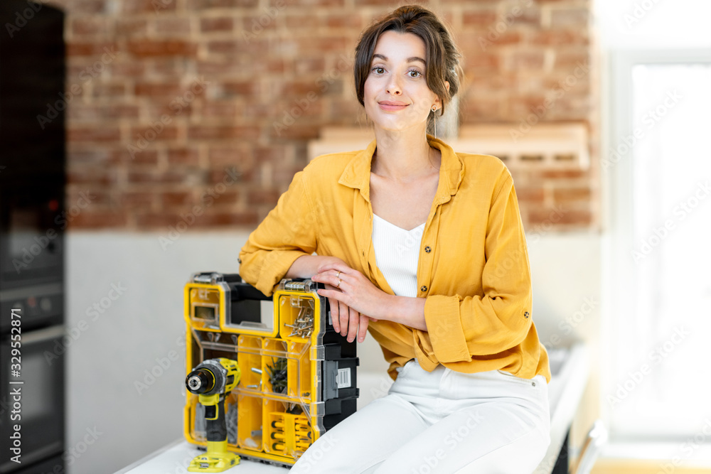 Portrait of a young and beautiful handy woman siting with instruments at the living room of apartmen