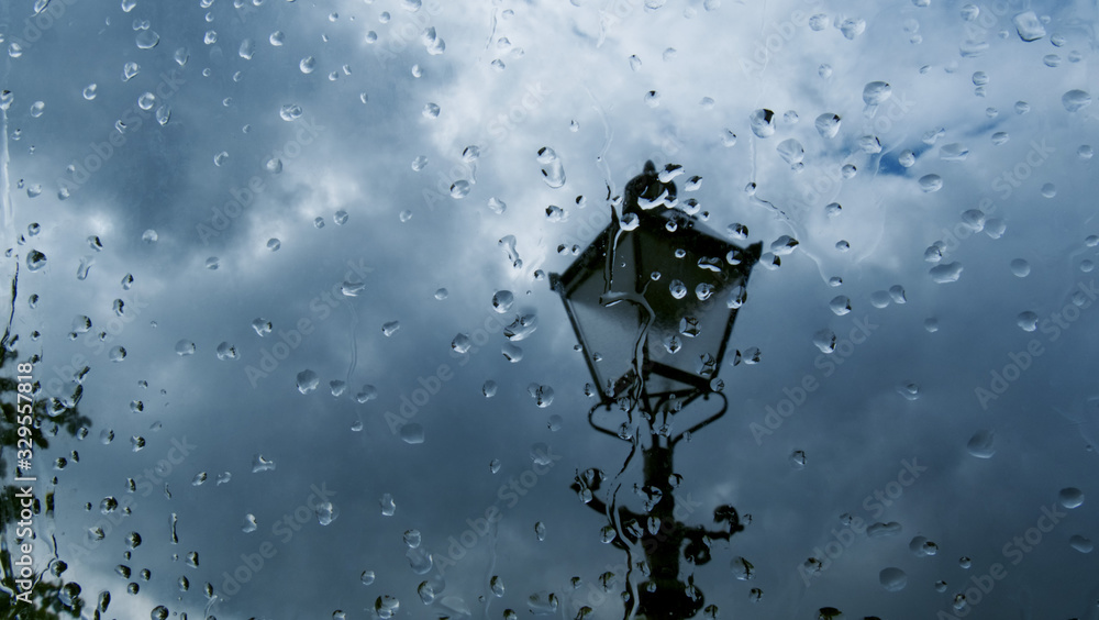 风暴中的路灯特写；雨点落在窗户上