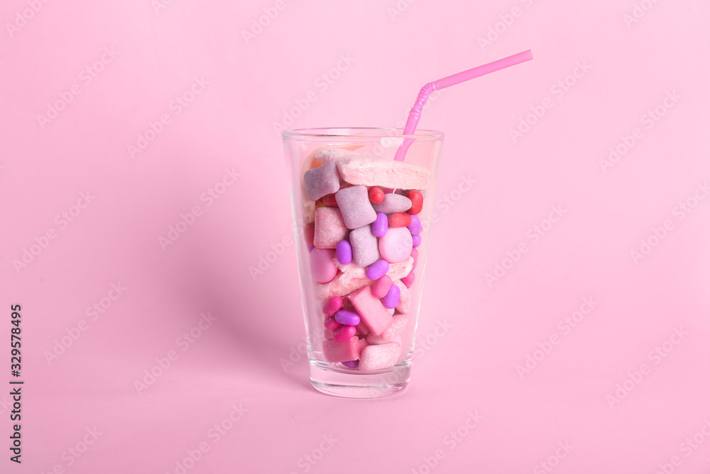 Glass with different chewing gums on color background