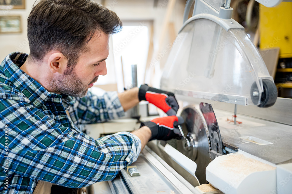 Mechanic repairs the circular saw machine and putting blade in carpentry workshop