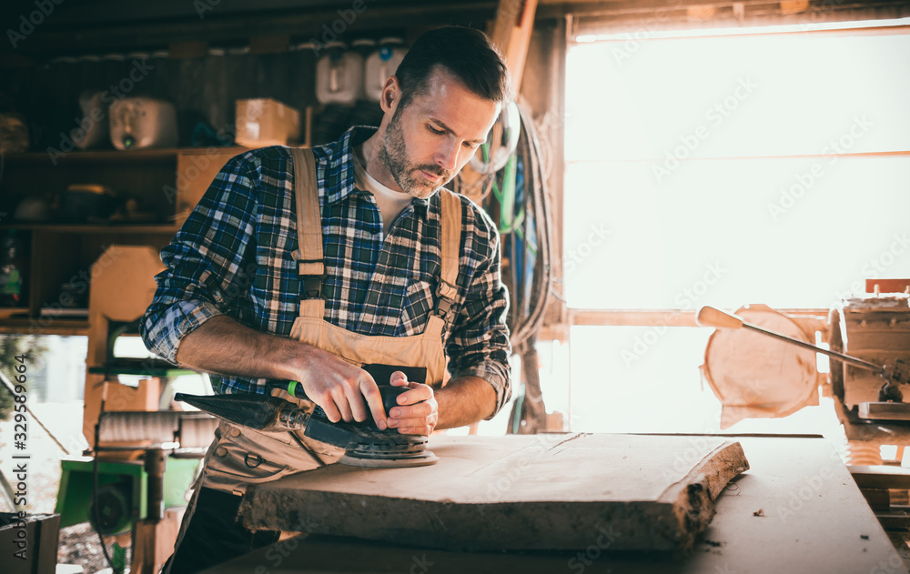 Carpenter using woodworking tools for craft work in carpentry workshop