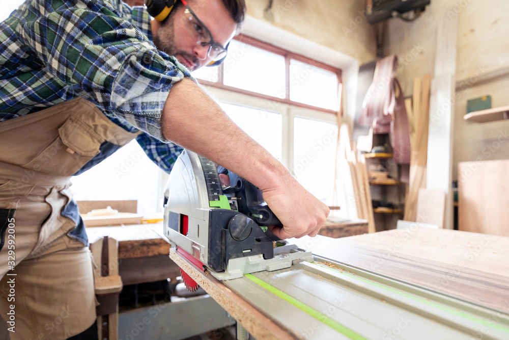 Carpenter using professional circular saw to cutting a wooden board in carpentry workshop