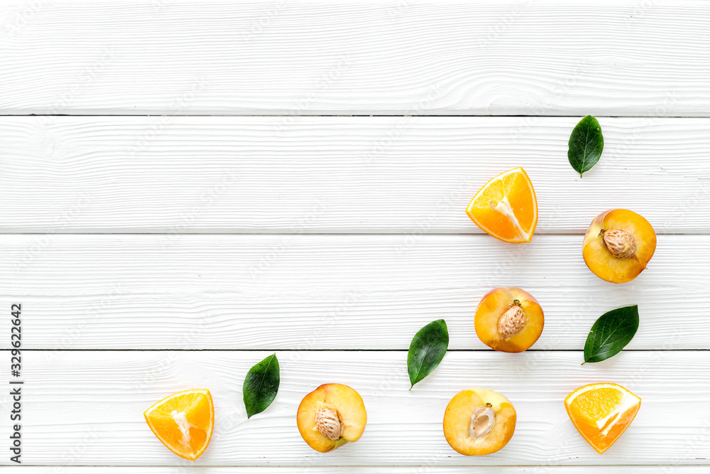 Peach slices and leaves pattern on white wooden background top-down copy space frame