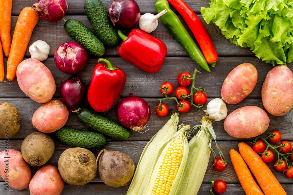 Fresh vegetables still life. Potato, cucumber, beet carrot, greenery on dark wooden background top-d