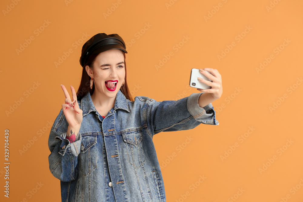 Emotional young woman taking selfie on color background