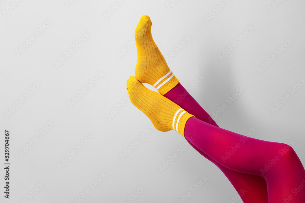 Legs of young woman in socks and tights on light background