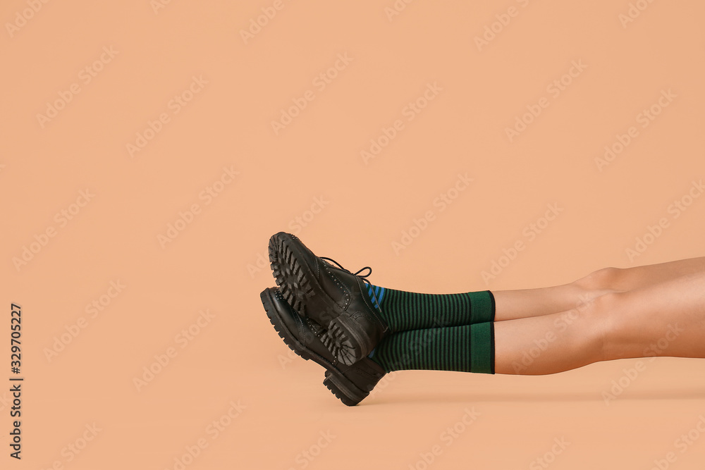 Legs of young woman in socks and shoes on color background