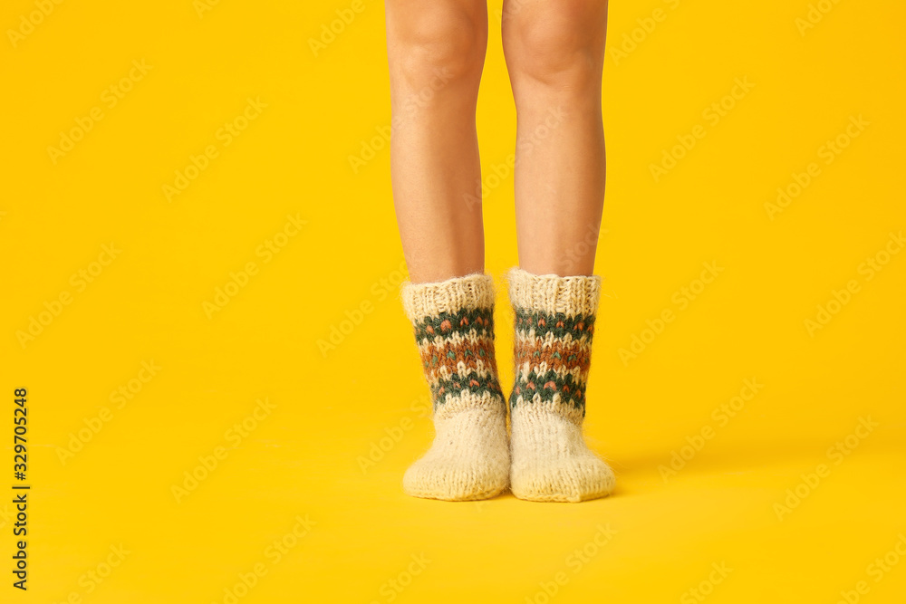 Legs of young woman in warm knitted socks on color background