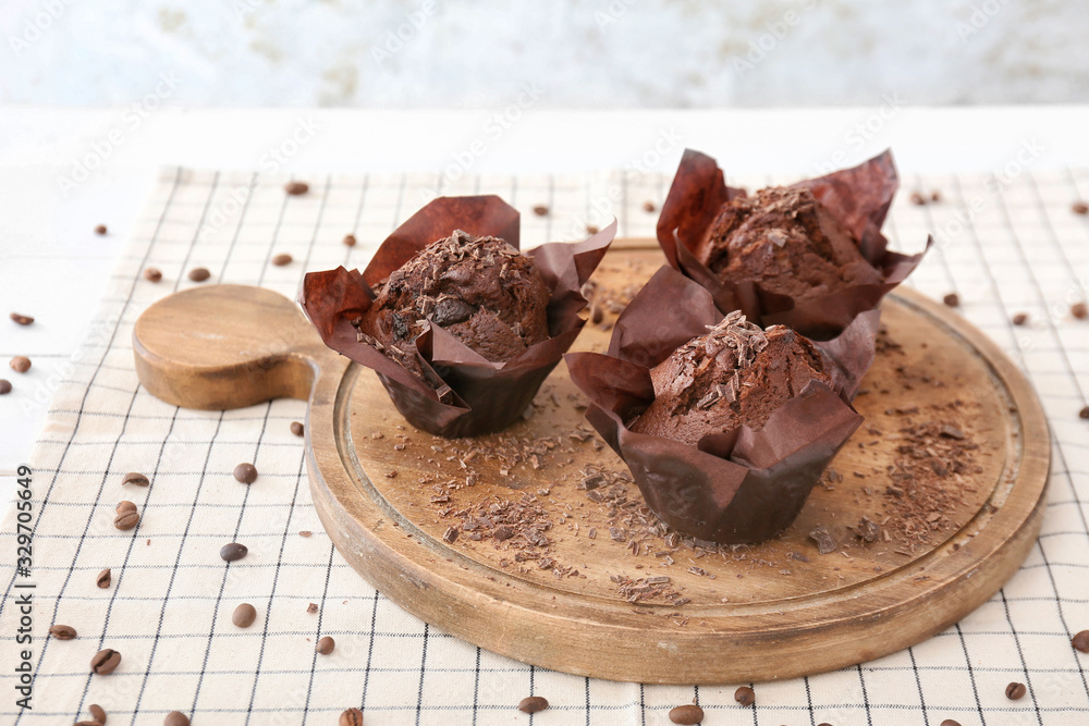 Board with tasty chocolate muffins on table