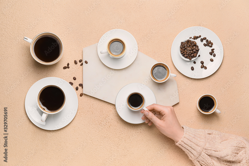 Female hand and cups of different coffee on color background