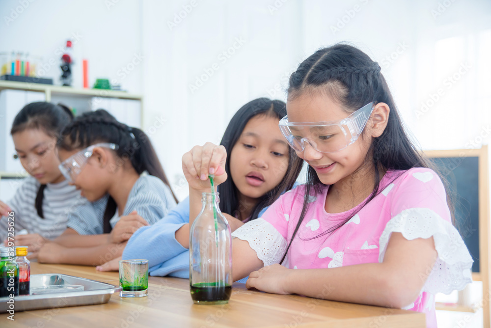 Group of young asian schoolgirls doing experiment in chemistry classroom.