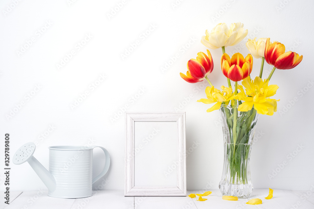 Tulip flower in glass vase with picture frame place on white wooden table background against clean w