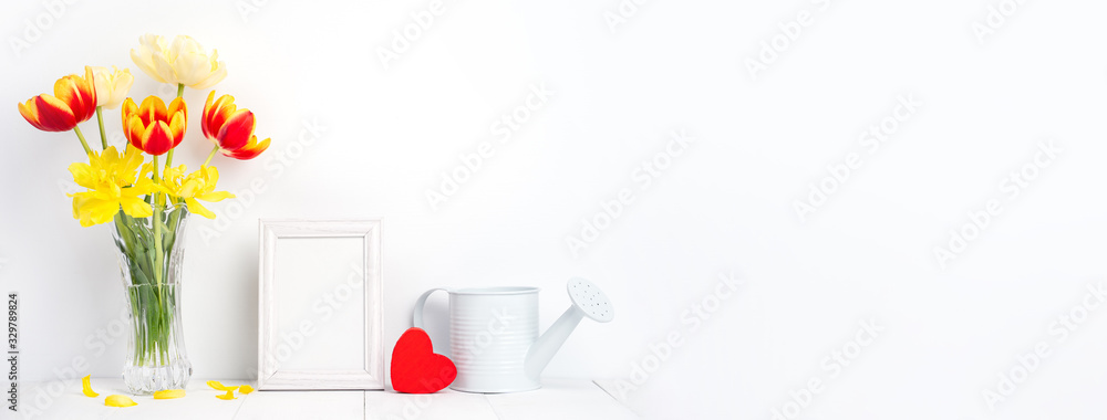 Tulip flower in glass vase with picture frame place on white wooden table background against clean w