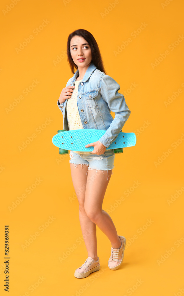 Cool young woman with skateboard on color background