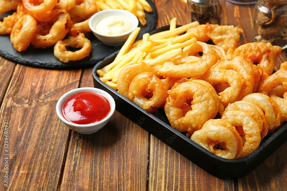 Crispy fried onion rings and sauces on table