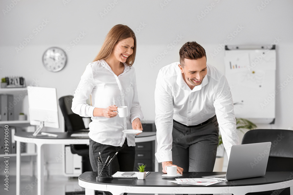 Young colleagues drinking coffee while working in office