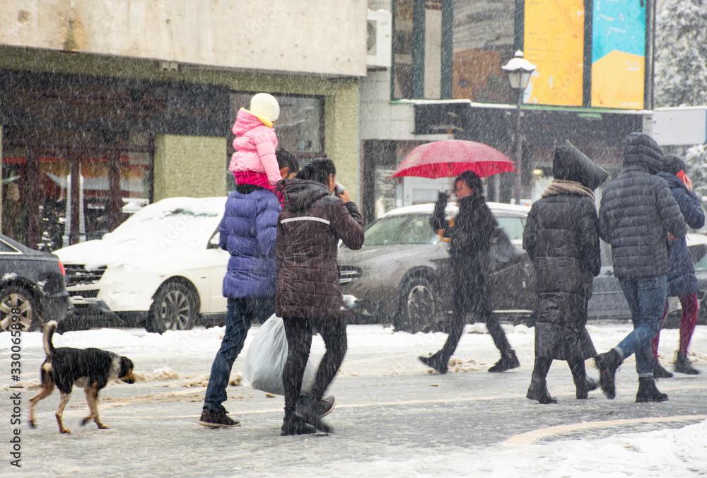 忙碌的城市人在冬天的雪天走在街上。故意的动作模糊