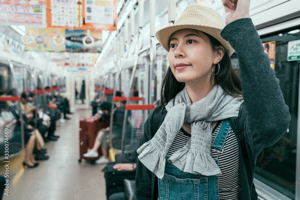 年轻的旅行女性在现代有轨电车中拿着把手。快乐的女乘客享受旅程