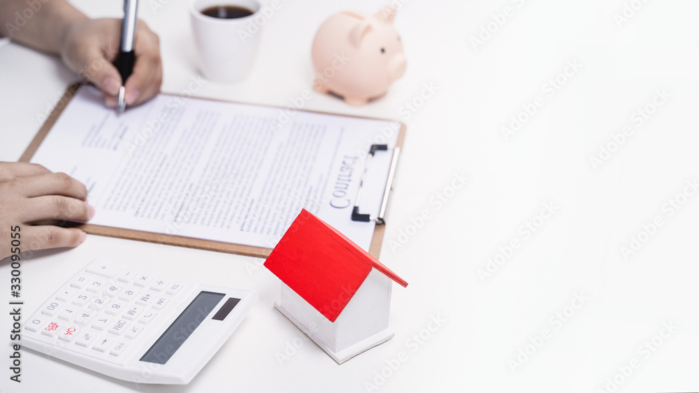 Business concept - Young Asian man in blue shirt calculates, signs agreement contract to buy a house