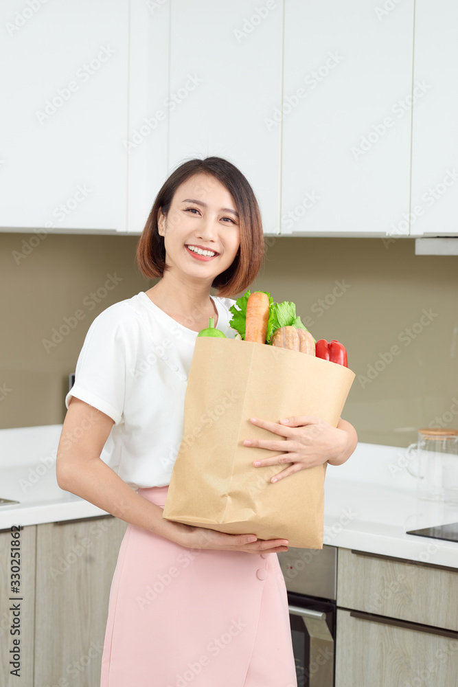 快乐的年轻亚洲女人，购物袋里有蔬菜。饮食理念。