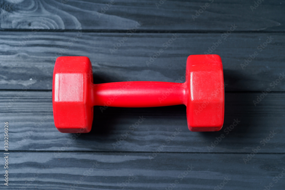 Red dumbbell for fitness isolated on dark background.