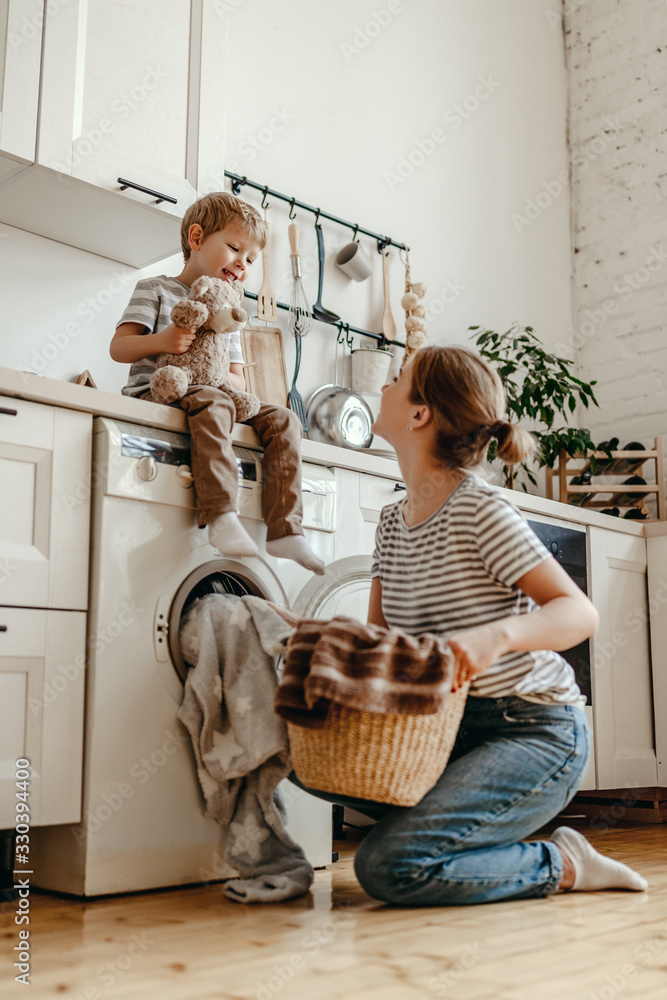 Happy family mother housewife and child   in laundry with washing machine .